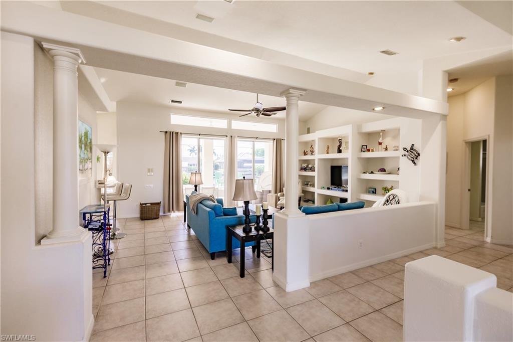 Living room with built in features, ceiling fan, and light tile patterned flooring
