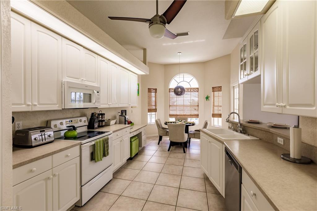 Kitchen featuring white appliances, ceiling fan, sink, pendant lighting, and light tile patterned floors