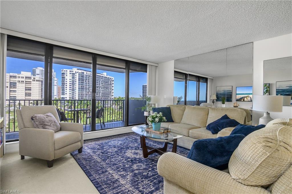 Living room with a textured ceiling, carpet floors, and floor to ceiling windows