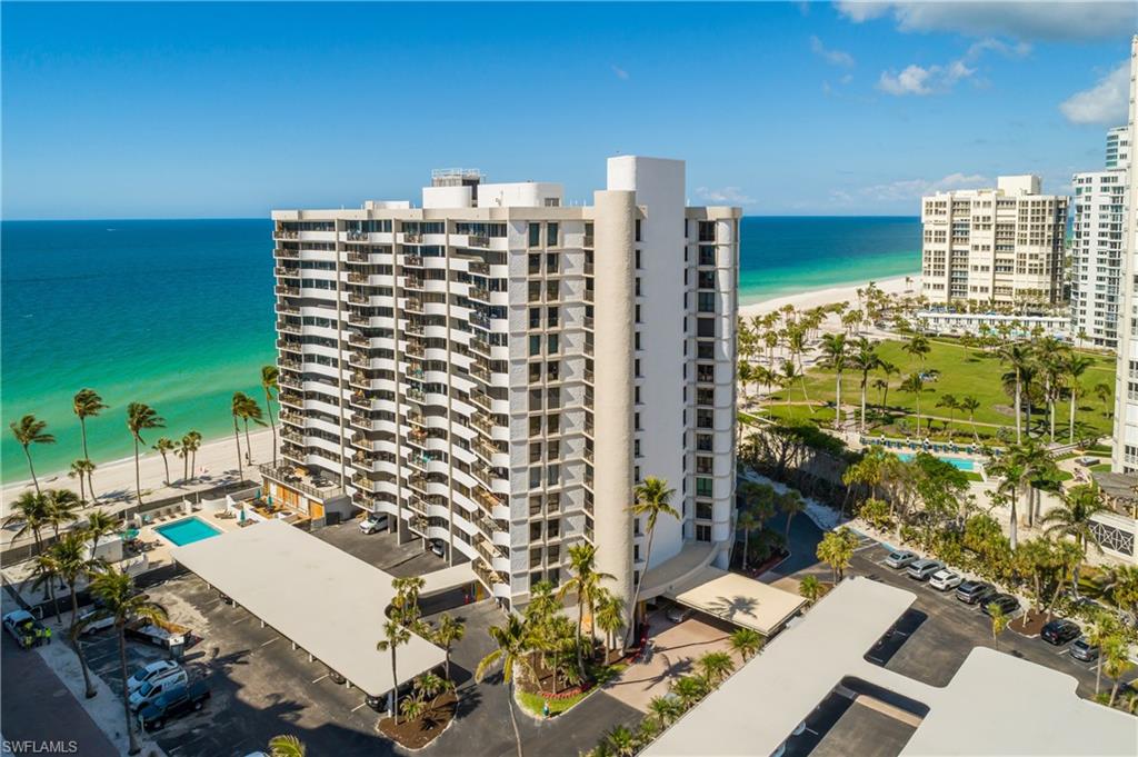 View of apartment building / complex featuring view of water and beach