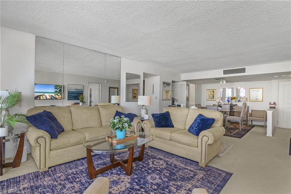Living room with carpet floors, a textured ceiling, and healthy amount of natural light