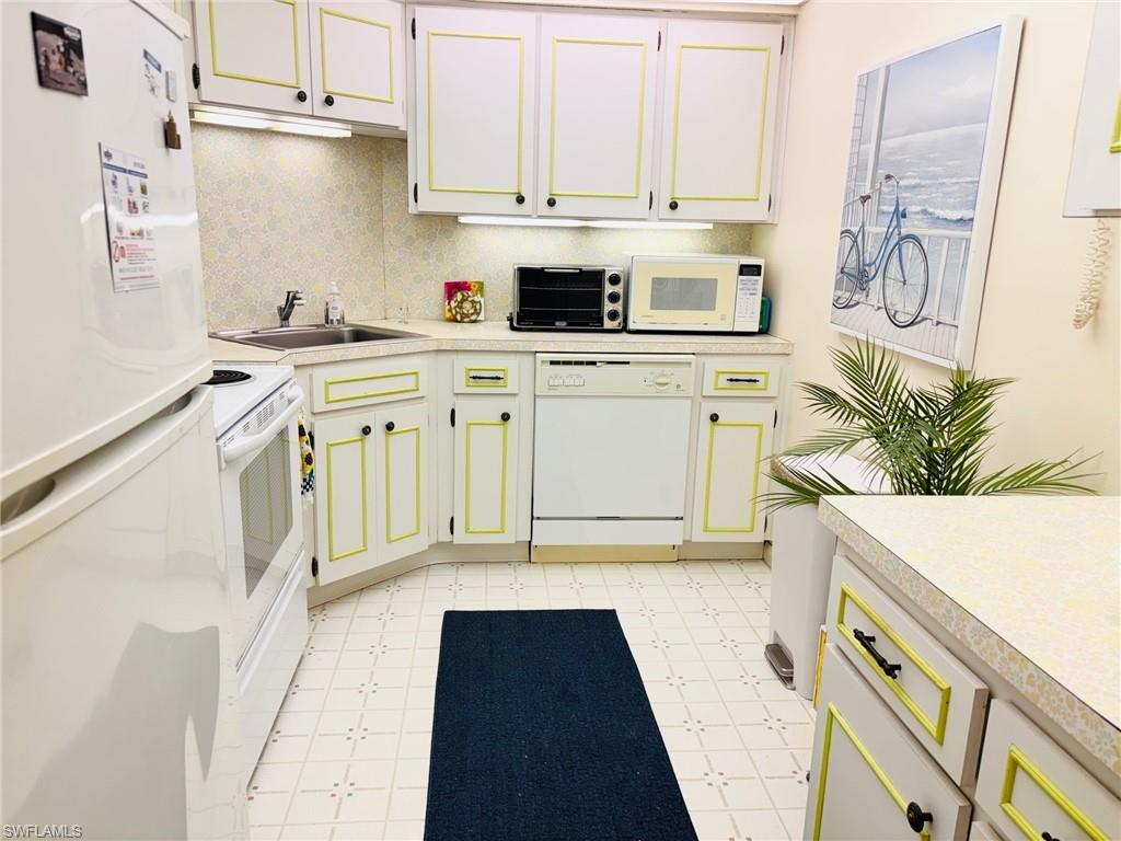 Kitchen with white appliances, light flooring, and light countertops