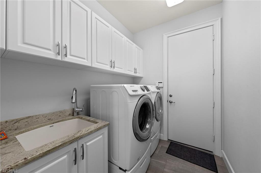Dedicated laundry room featuring white shaker-style cabinetry with chrome hardware, an integrated laundry sink with a single-handle faucet, and light-toned countertop
