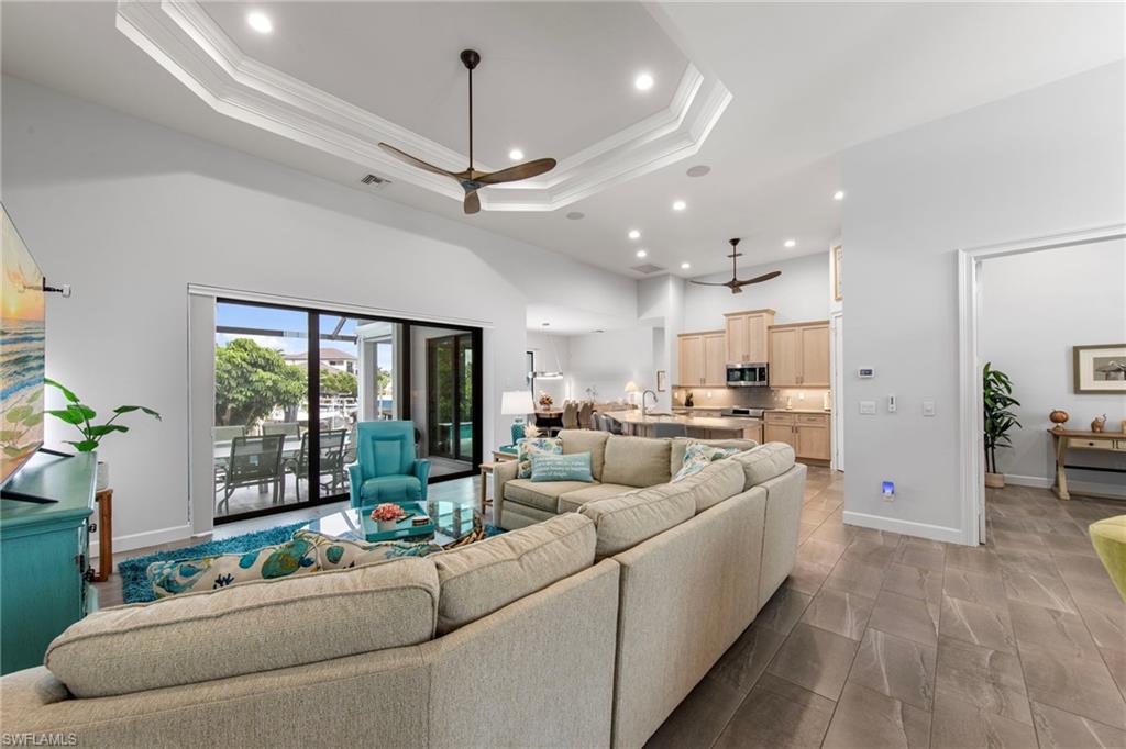 Living area featuring vaulted ceilings with recessed lighting, large format tile flooring, and sliding glass doors opening to an outdoor lanai