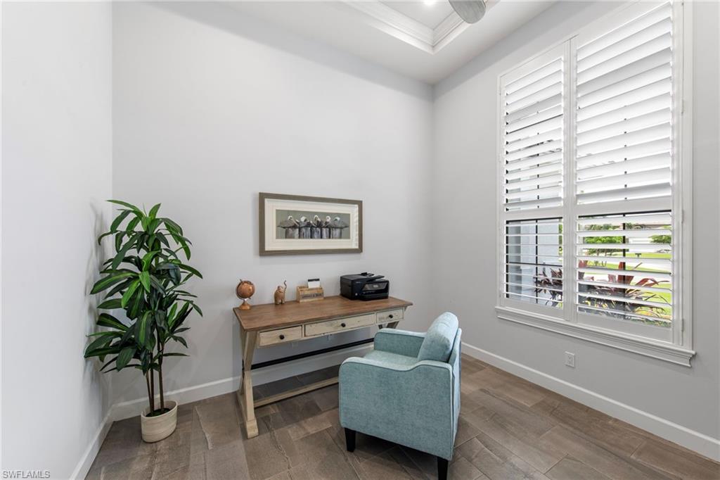 Room featuring wood-finish flooring, white baseboards, and a large window with white plantation shutters