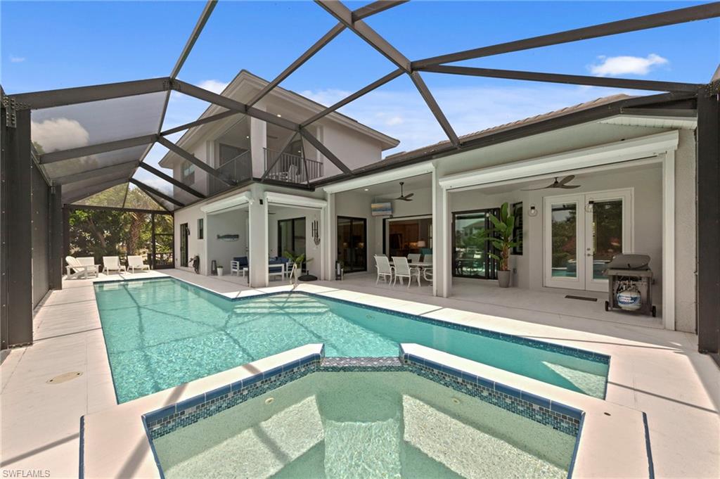 Screened outdoor living area featuring a rectangular pool and integrated spa with mosaic tile detailing