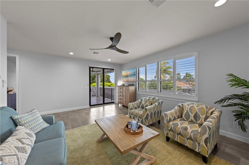 Living area featuring wood-finish flooring, recessed lighting, ceiling fan, and white plantation shutters
