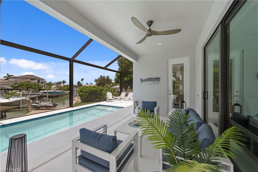 Screened lanai featuring a ceiling fan, direct pool access, and waterfront views