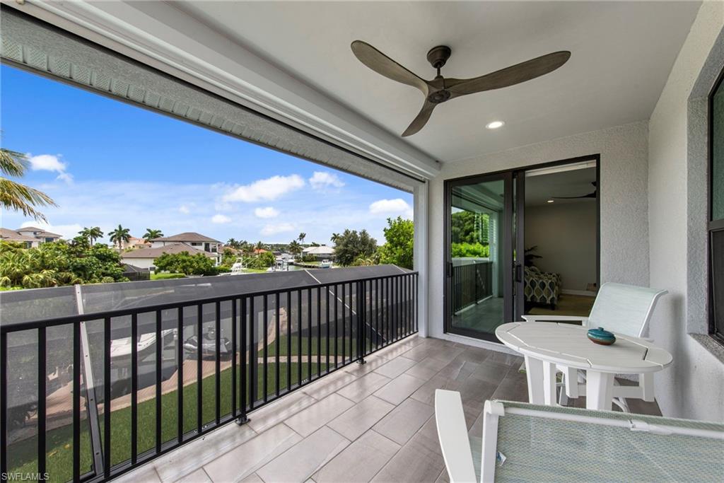 Covered balcony featuring tile flooring, a ceiling fan, and sliding glass doors