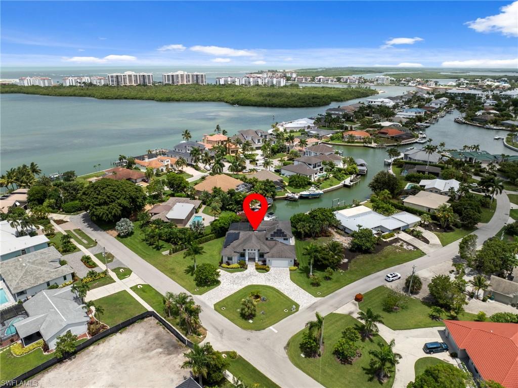 Waterfront property featuring a private boat dock, lush tropical landscaping, and a paver driveway