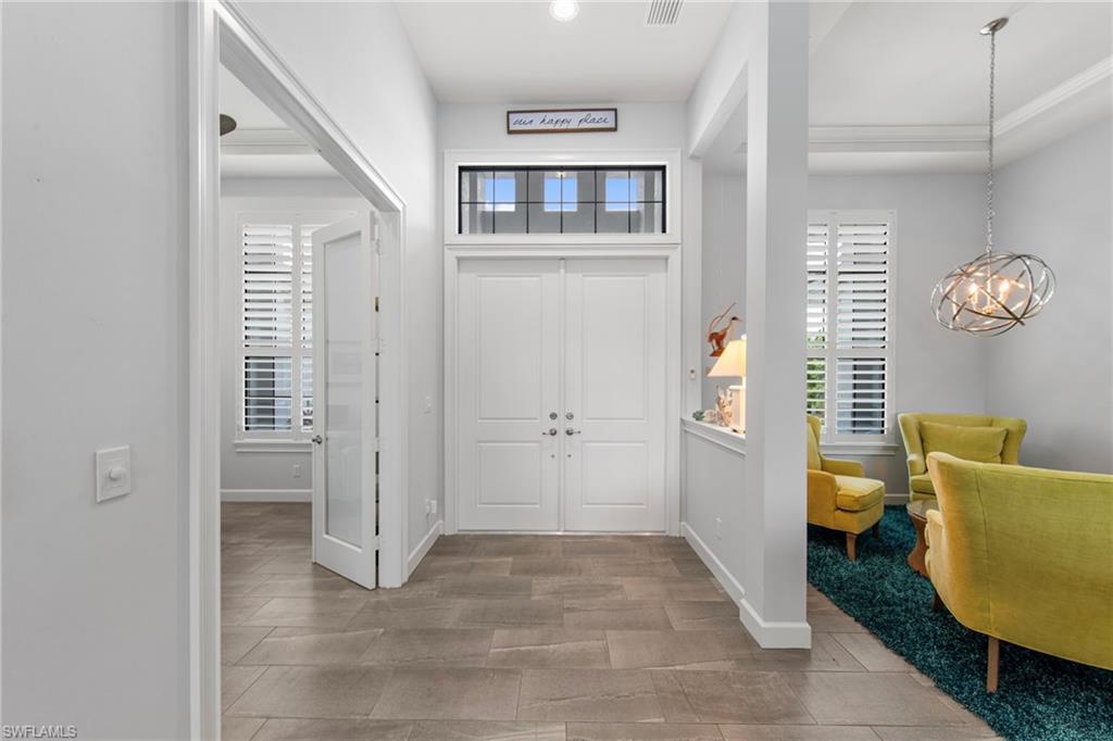 Entryway featuring a double door entrance with transom window, tile flooring, tray ceiling, and an architectural pendant light fixture