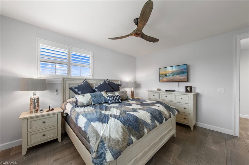 Spacious room featuring light wood-finish flooring, a ceiling fan, and window shutters