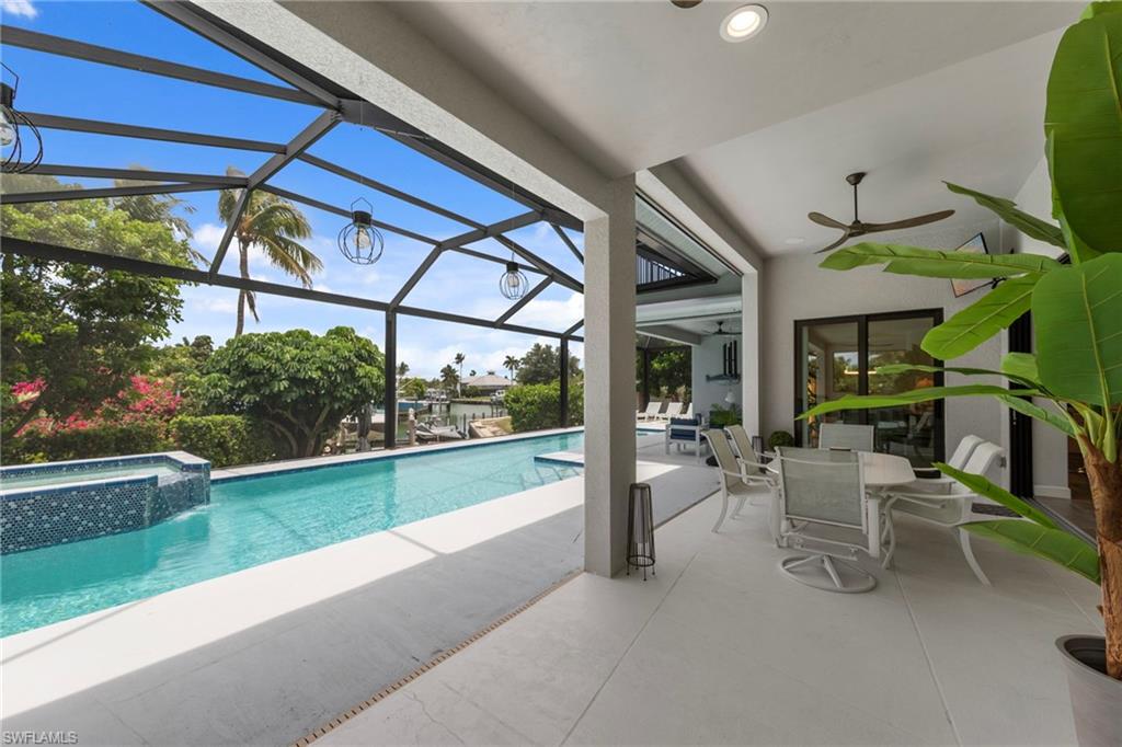 Screened lanai featuring a linear pool with an integrated spa, a textured blue tile accent, and an overhead lighting system