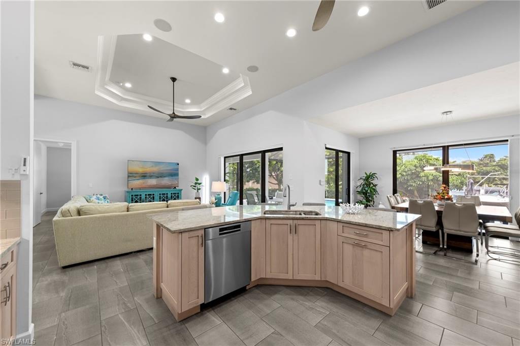 Open-concept living area featuring a kitchen island with light wood cabinetry and a light-colored countertop