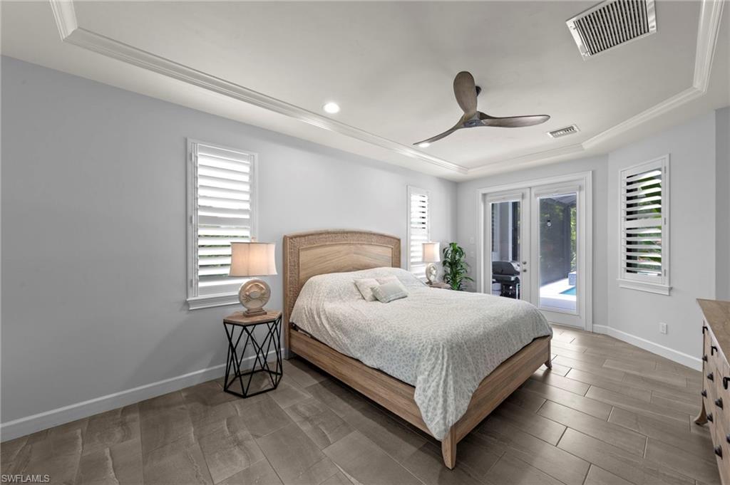 Recessed lighting, crown molding, and a tray ceiling accent this room featuring plank-style tile flooring