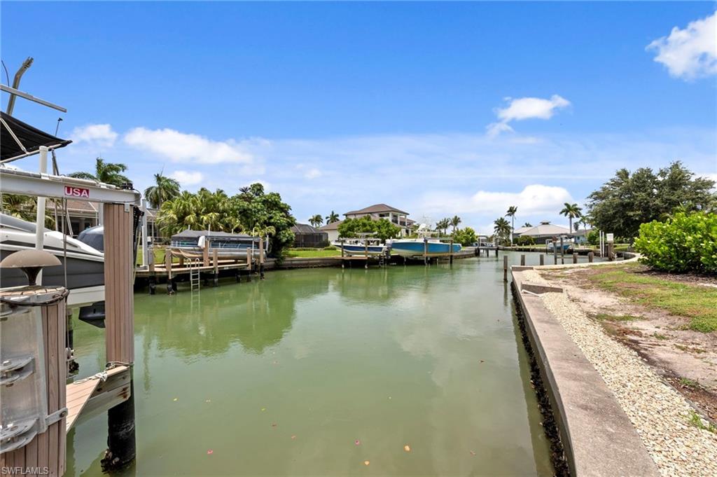 Waterfront canal with an installed boat lift and dock featuring a concrete seawall
