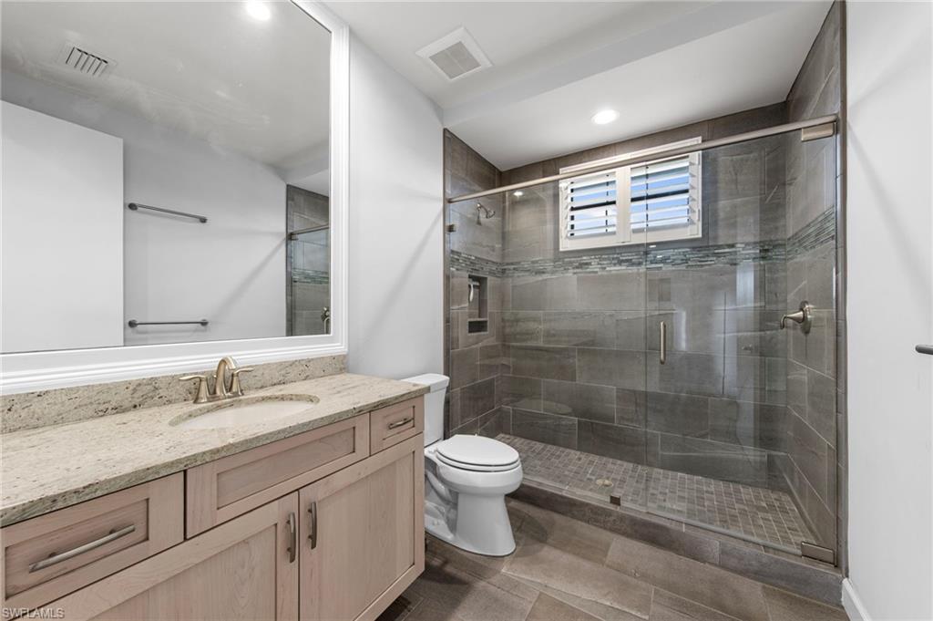 upstairs bathroom featuring a single vanity with stone countertop, undermount sink, and light wood-finish cabinetry