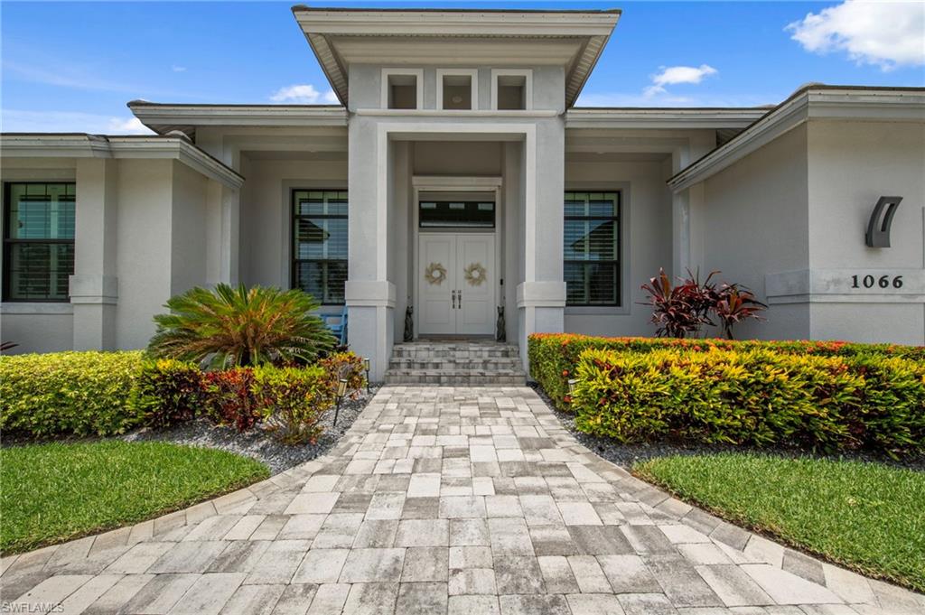 Contemporary stucco exterior with a prominent portico entry and double doors