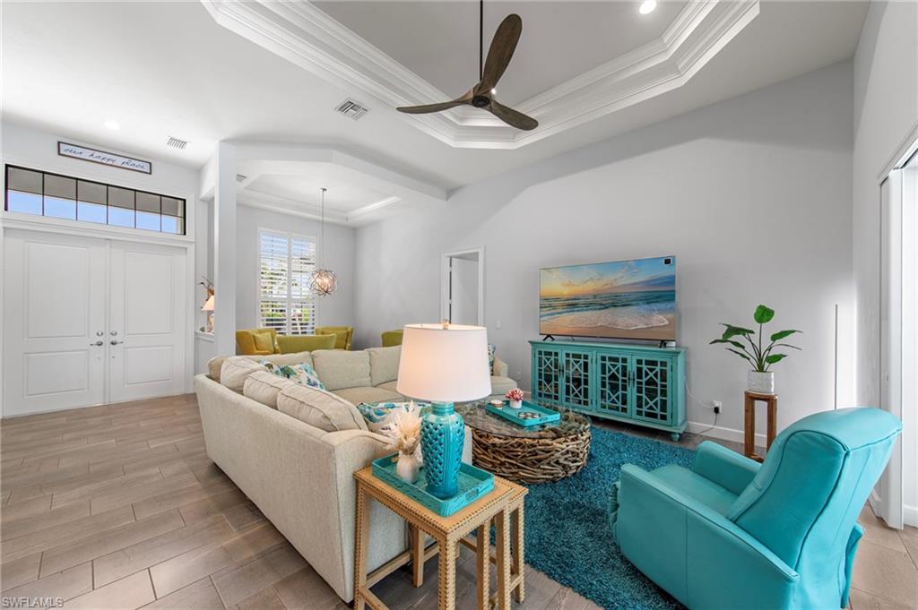Spacious living area featuring wood-finish flooring, a tray ceiling with a ceiling fan, and recessed lighting