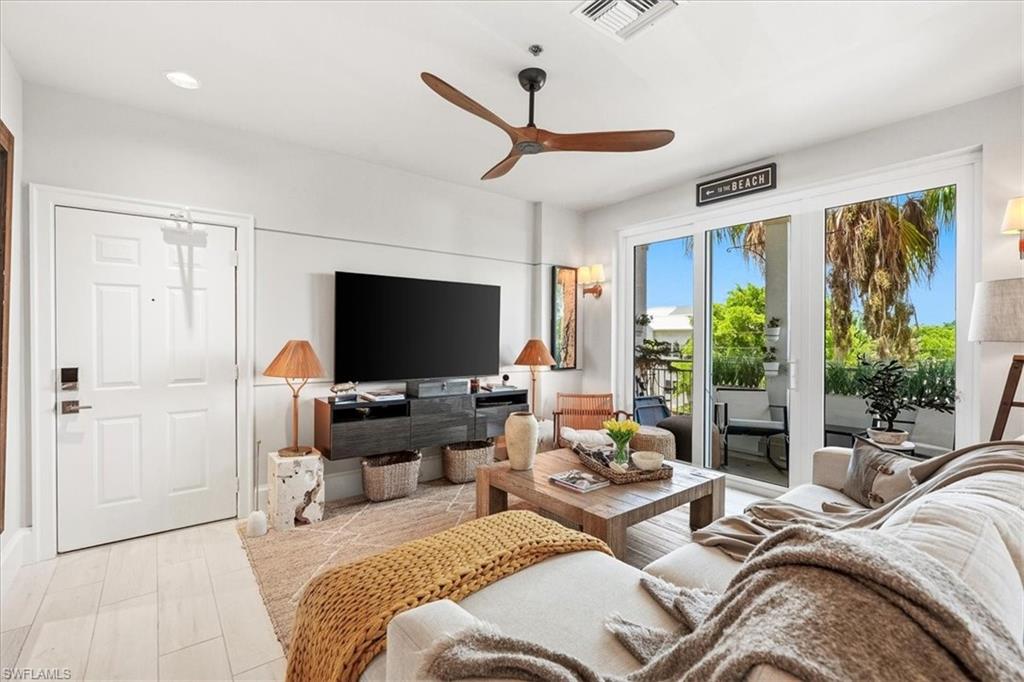 Bright living space featuring wood-finish flooring and a wood-bladed ceiling fan