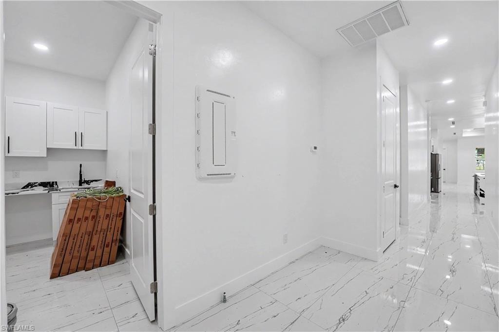 Bright hallway featuring polished tile flooring, recessed lighting, and a white interior door