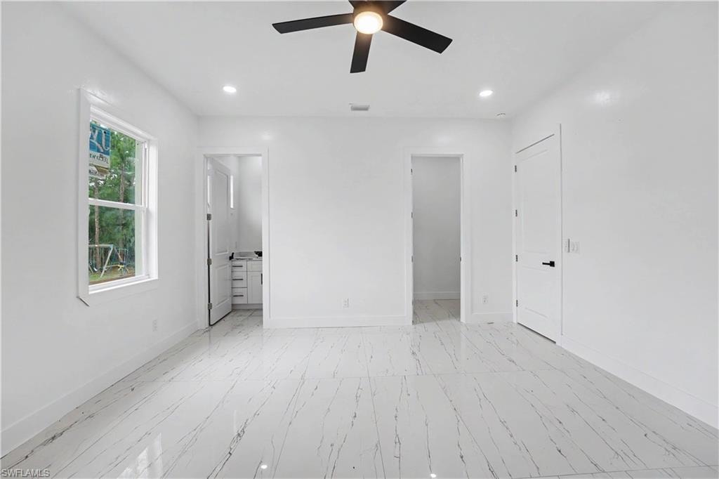 Spacious interior featuring marble-look tile flooring, white walls, and recessed lighting