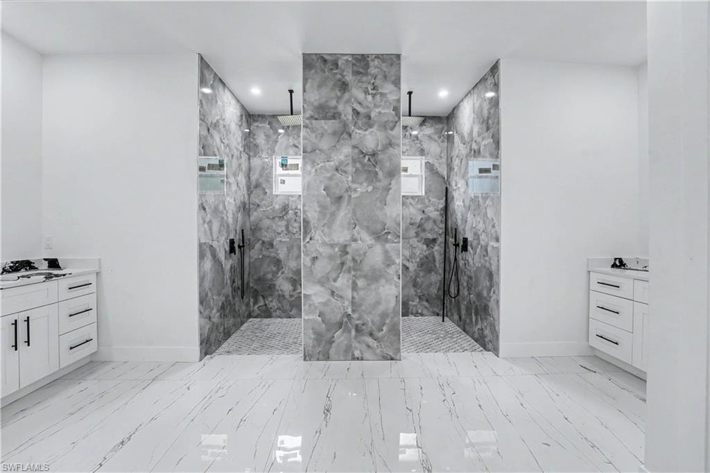 Spacious bathroom featuring two walk-in showers with grey-veined tile walls and mosaic tile flooring