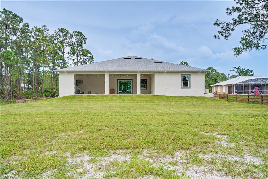 Expansive rear elevation featuring a stucco exterior, covered patio with multiple columns, and a large window with white trim
