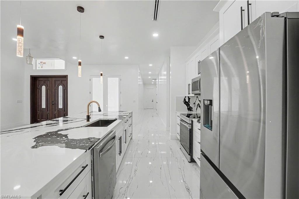Modern kitchen featuring an expansive island with a waterfall countertop, integrated sink, and bronze-finish faucet
