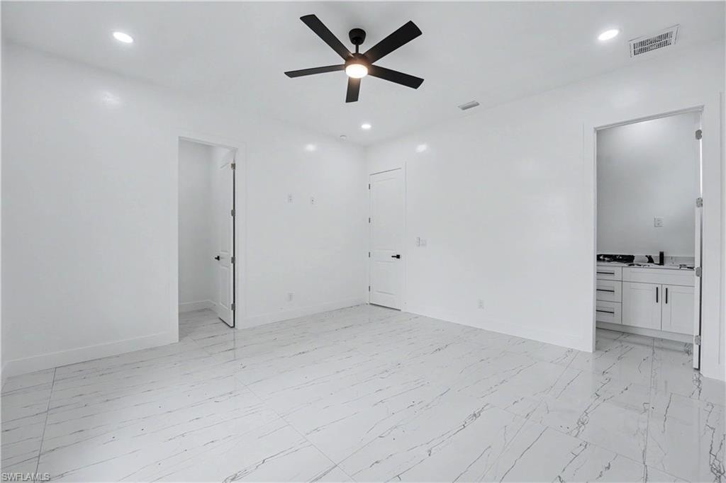 Spacious room featuring white walls and large format marble-look tile flooring
