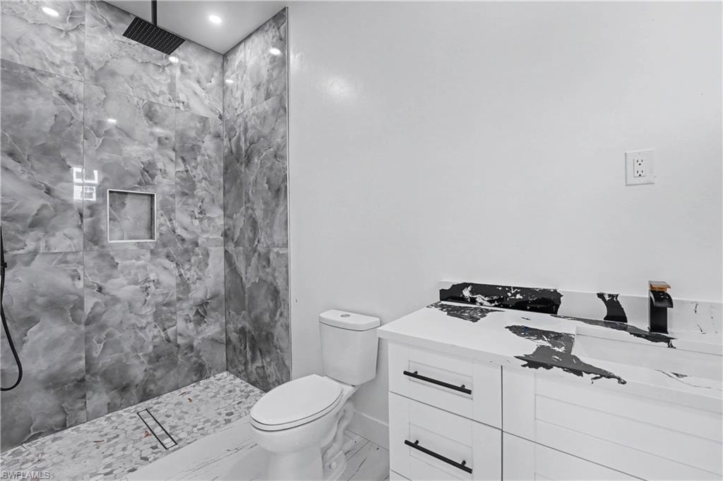 Modern bathroom featuring a tiled walk-in shower with a black rain showerhead, a built-in shower niche, and a pebble-tiled floor