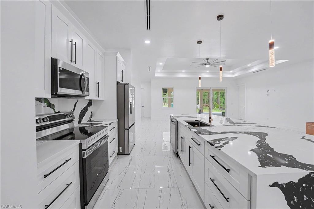 Modern kitchen featuring a large island with a waterfall edge, integrated sink, and sleek appliances