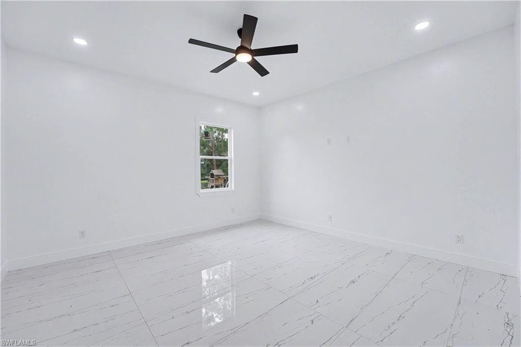 Spacious room featuring white walls, large format tile flooring, recessed lighting, a modern ceiling fan, and a single window