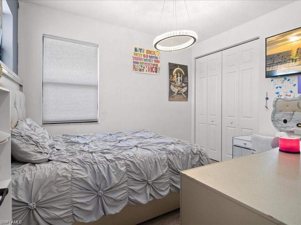 Bedroom featuring a window with roller shade, bi-fold closet doors, and overhead circular light fixture