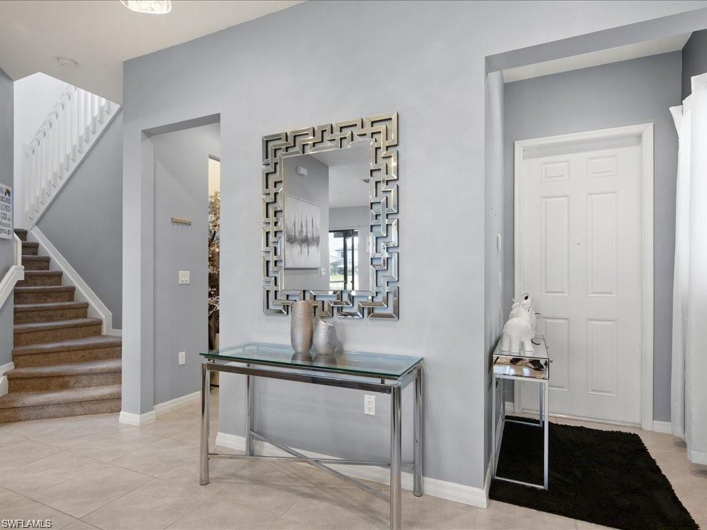 Spacious entryway featuring a paneled door, light gray wall paint, and large format tile flooring