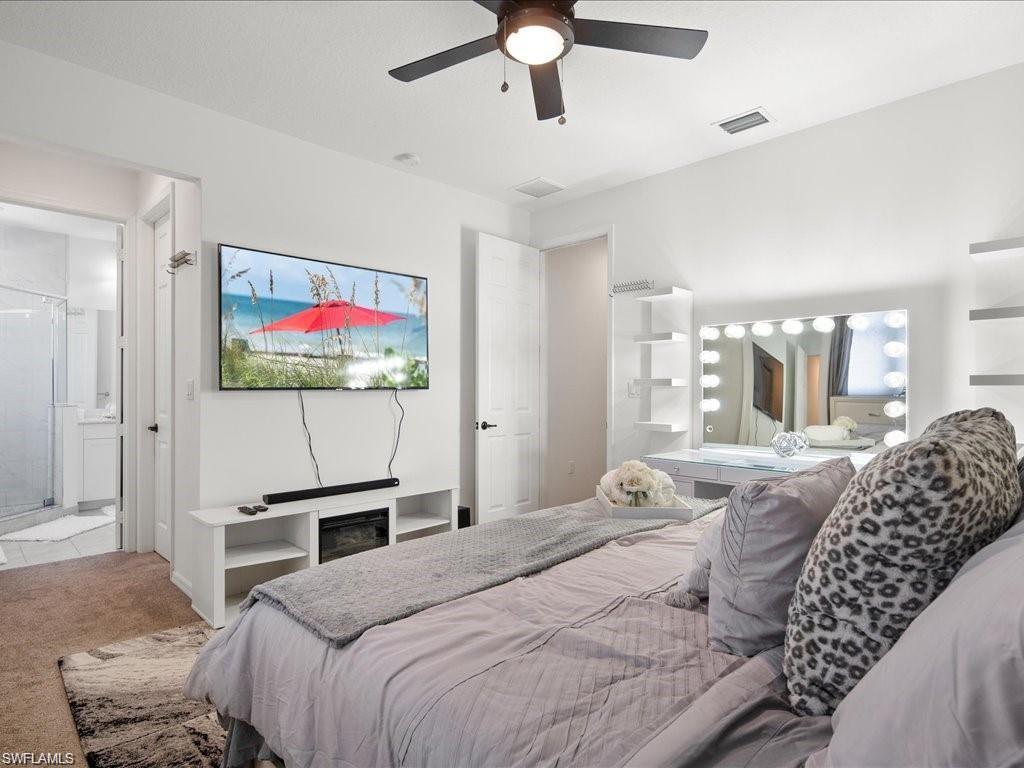 Bedroom featuring a ceiling fan with light fixture, built-in shelving, and a vanity with integrated lighting