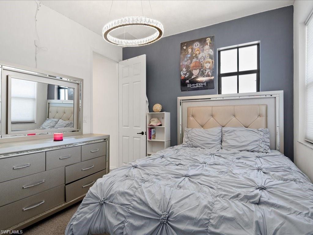 Room featuring a tufted upholstered headboard, a window with horizontal blinds, and a built-in shelving unit