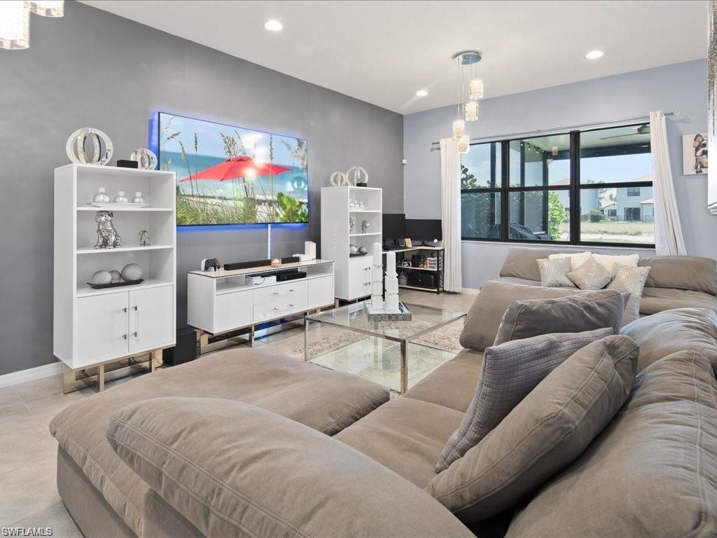 Living area featuring recessed lighting, a contemporary chandelier, a large window with white drapery, and tile flooring