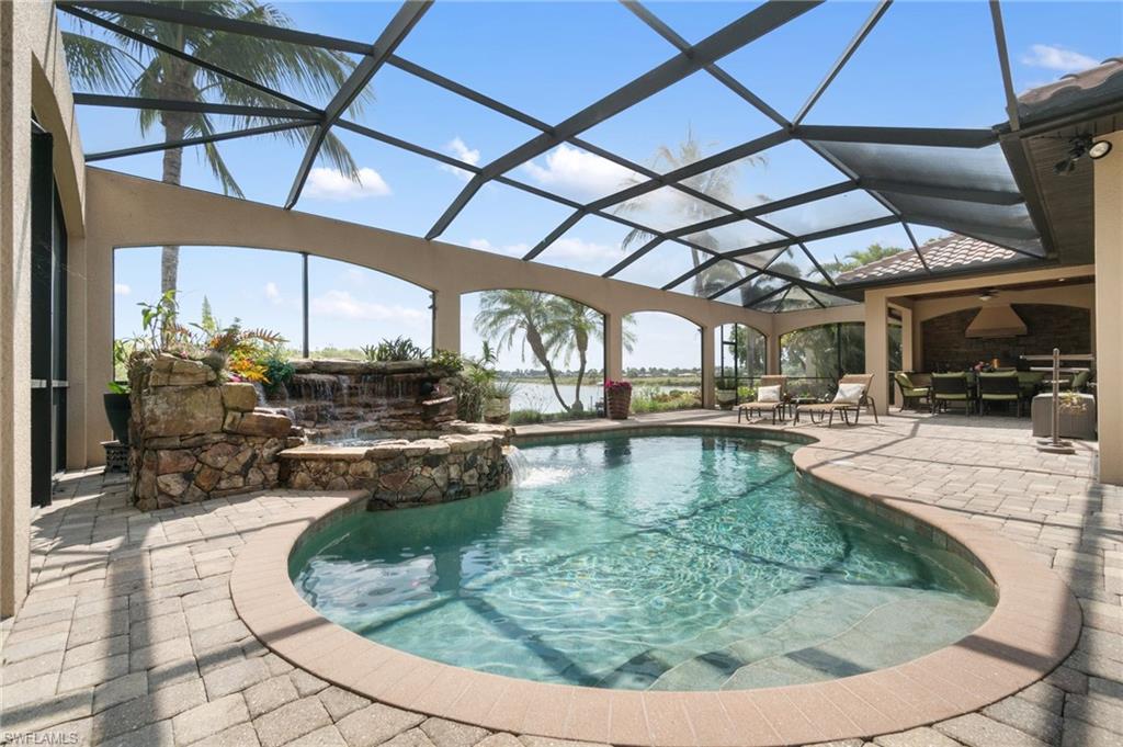 Screened lanai featuring a curved swimming pool with integrated spa and rock waterfall