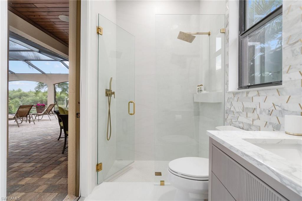 Modern bathroom featuring a glass-enclosed shower with gold-toned fixtures, a rain shower head, and a built-in shower niche