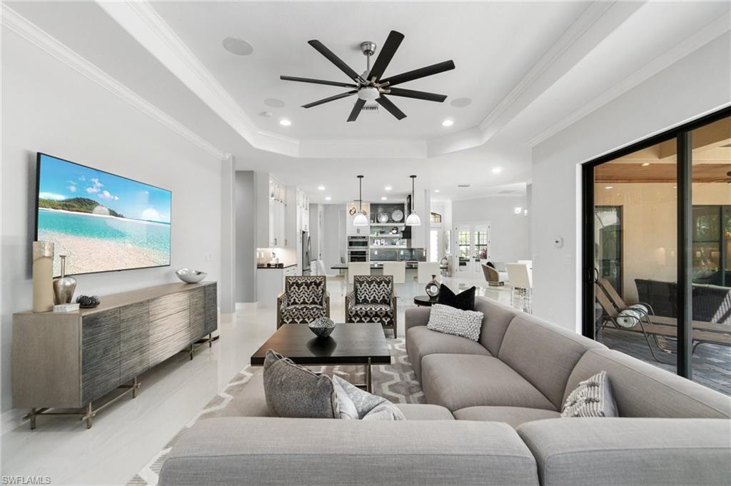 Spacious living area featuring high tray ceilings, recessed lighting, and a large ceiling fan