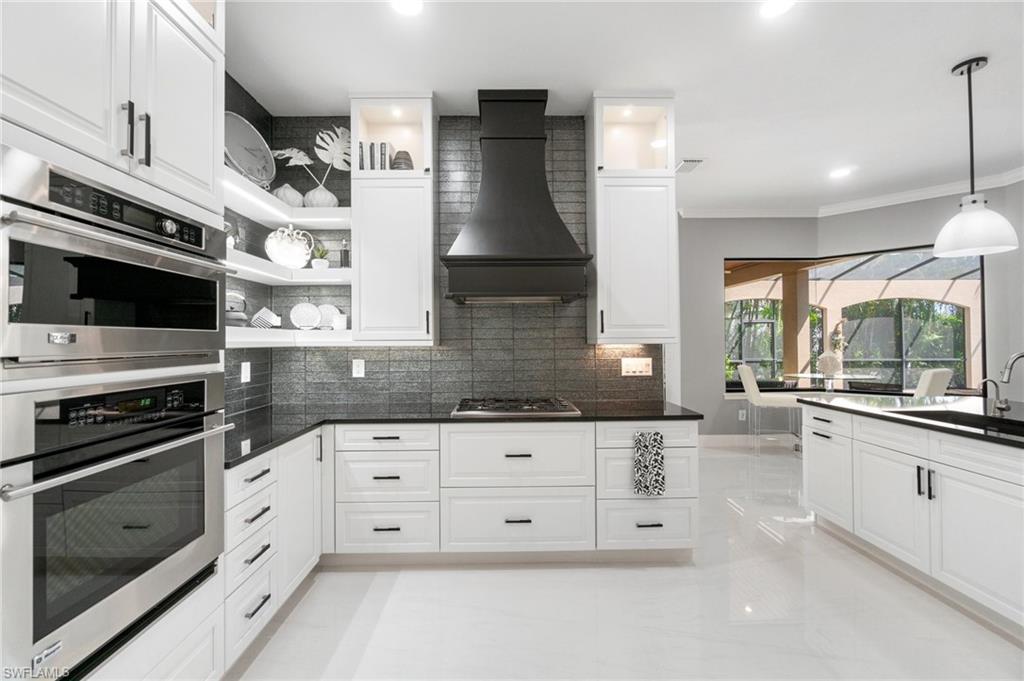 Contemporary kitchen featuring white cabinetry, dark countertops, and stainless steel built-in double ovens