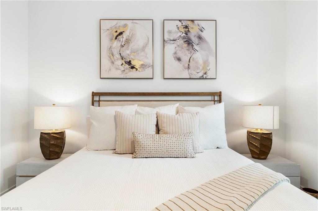 Bedroom featuring a prominent headboard, two coordinated bedside tables, and matching lamps with textured bases