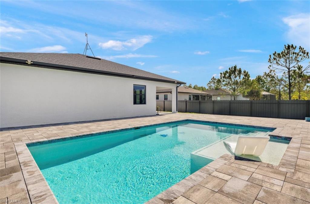 Rectangular swimming pool featuring a tanning ledge, surrounded by paver decking