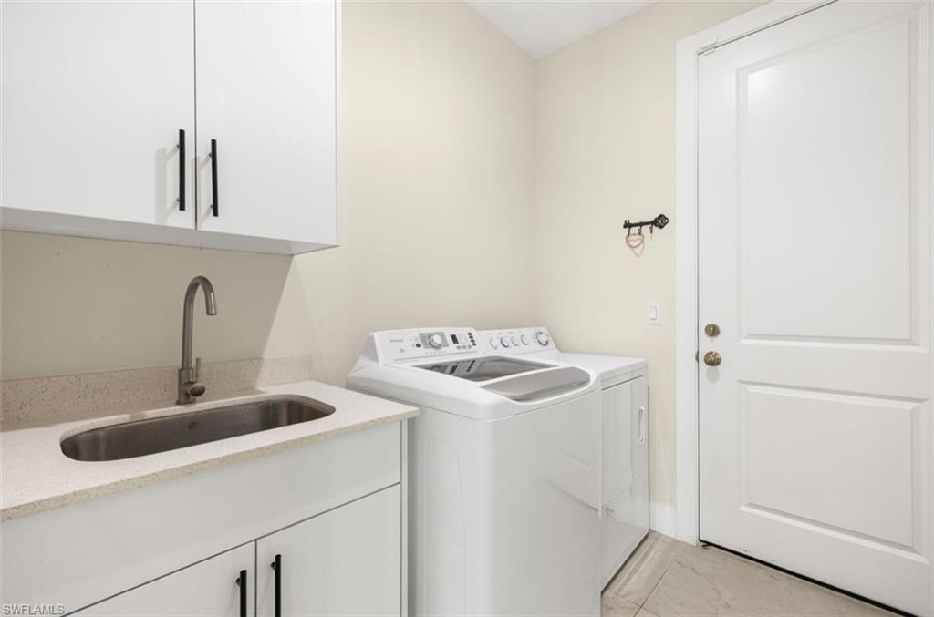Dedicated laundry area featuring a utility sink with a gooseneck faucet, light-toned countertop, and white cabinetry with dark hardware