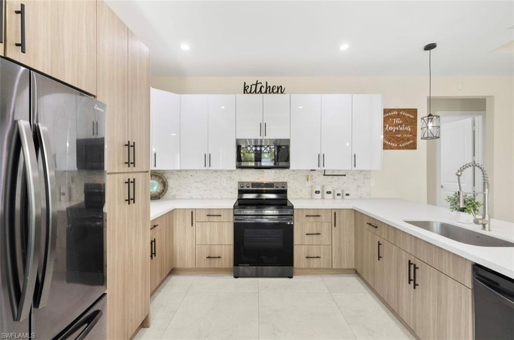 Modern kitchen featuring two-tone cabinetry with light wood-finish lower cabinets and glossy white upper cabinets
