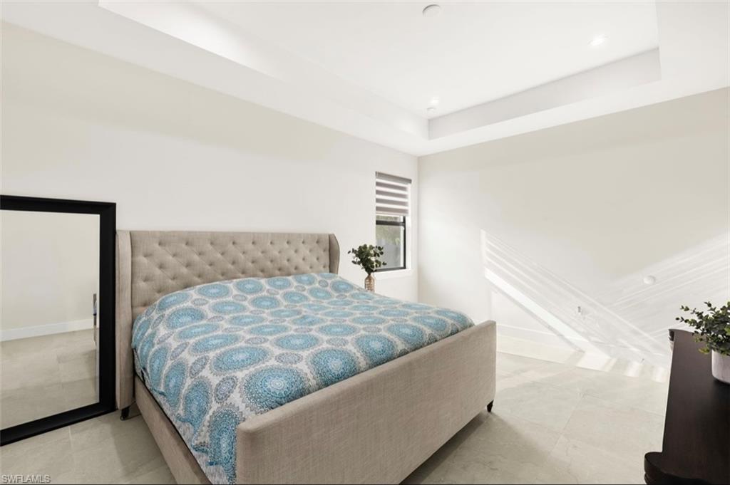 Spacious room featuring a tray ceiling, recessed lighting, and large format tile flooring