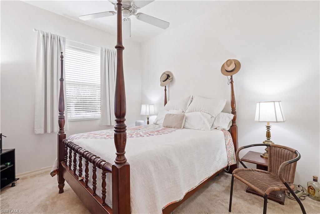 Bedroom featuring neutral wall paint, carpet flooring, a ceiling fan, and a window with blinds and drapes
