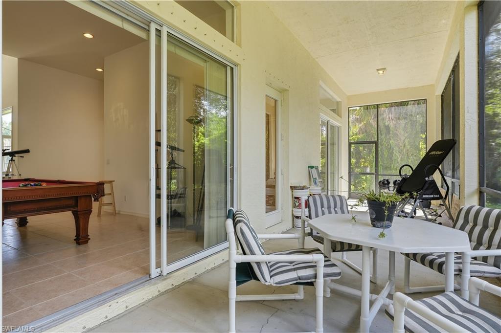 Screened patio with concrete flooring, textured ceiling, and a large sliding glass door opening to an interior room with tile flooring