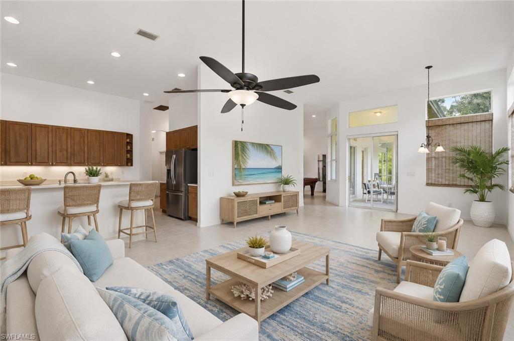 Open-concept living area featuring light-toned flooring, a kitchen island with seating, a ceiling fan, recessed lighting, Furnishings virtually Staged